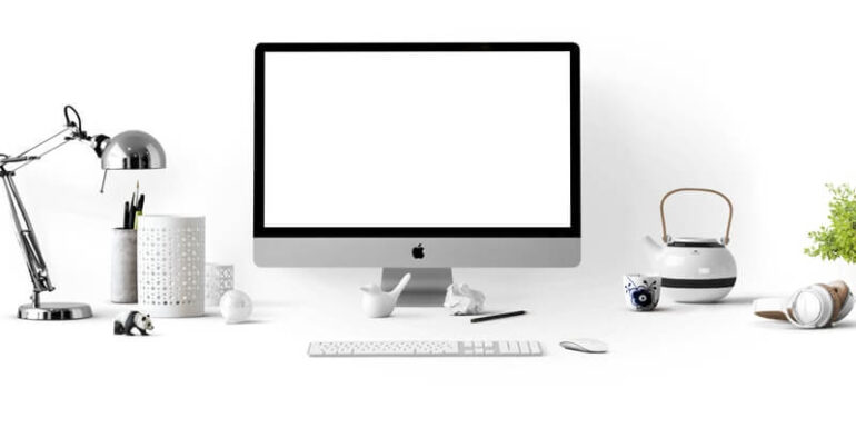 A desktop monitor with a blank white screen sitting on a white desk.